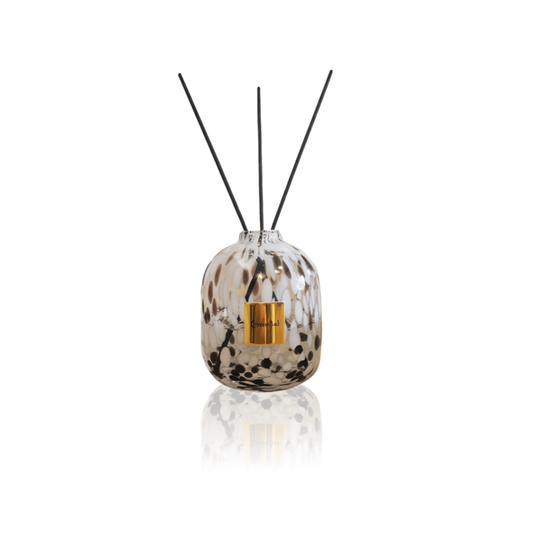 Isolated product shot of the Greenitial reed diffuser vessel, featuring a handcrafted white glass bottle with black leopard patterns.