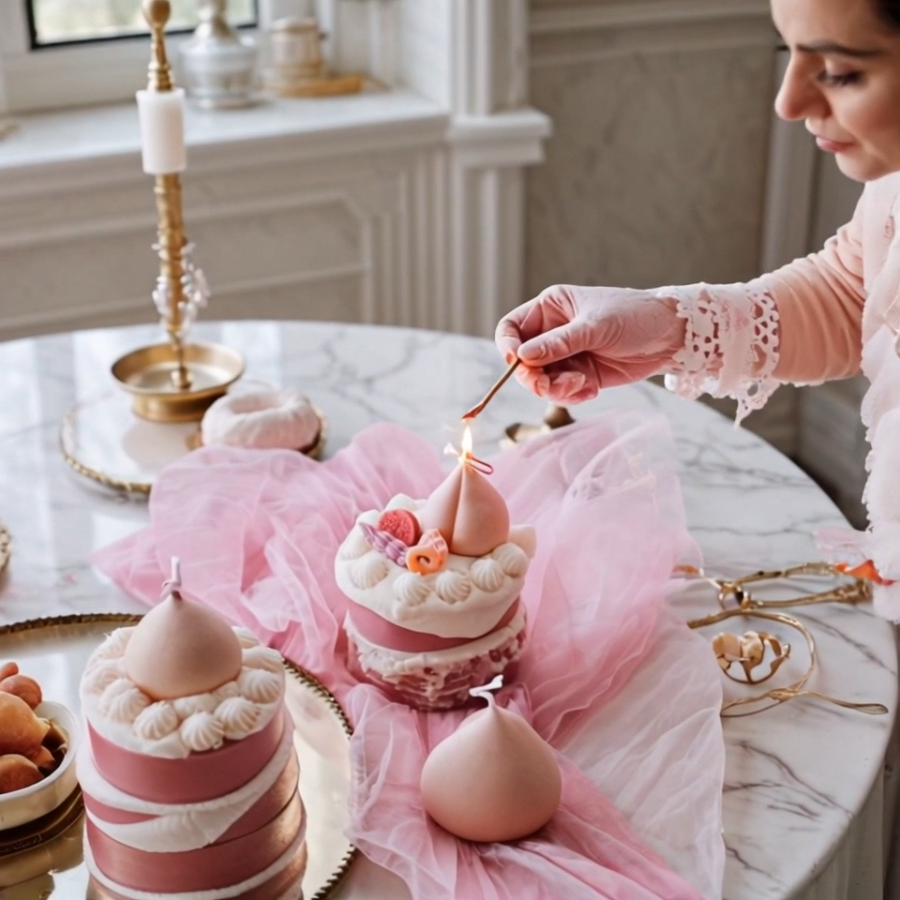 An elegant woman in an afternoon tea setting, lighting the realistic peach cake scented candle on a vintage table.
