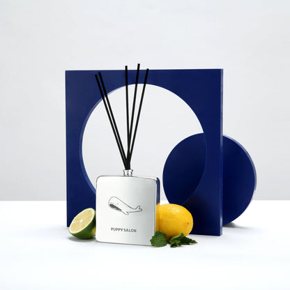 Lifestyle image of the Puppy Salon '52 Hertz' reed diffuser amidst lemons and limes, hinting at its bright, enigmatic citrus fragrance for modern interiors.