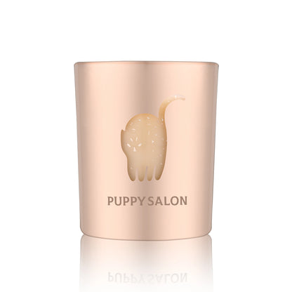 Isolated view of the Puppy Salon cat-inspired candle. The rose gold cut-out glass jar creates a warm, glowing pattern when lit.