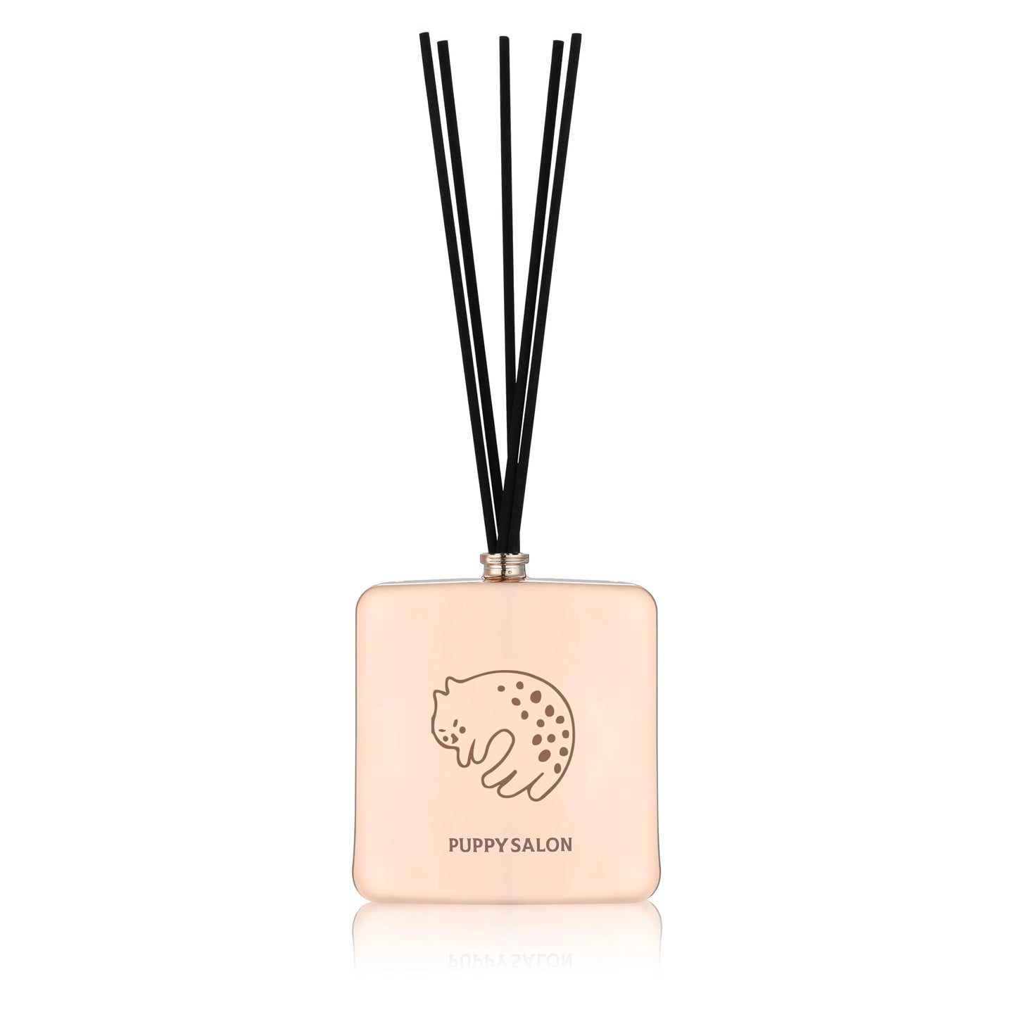 Isolated view of the Puppy Salon cat-inspired reed diffuser. The rose gold glass bottle with intricate cut-out designs adds a modern touch to any space.