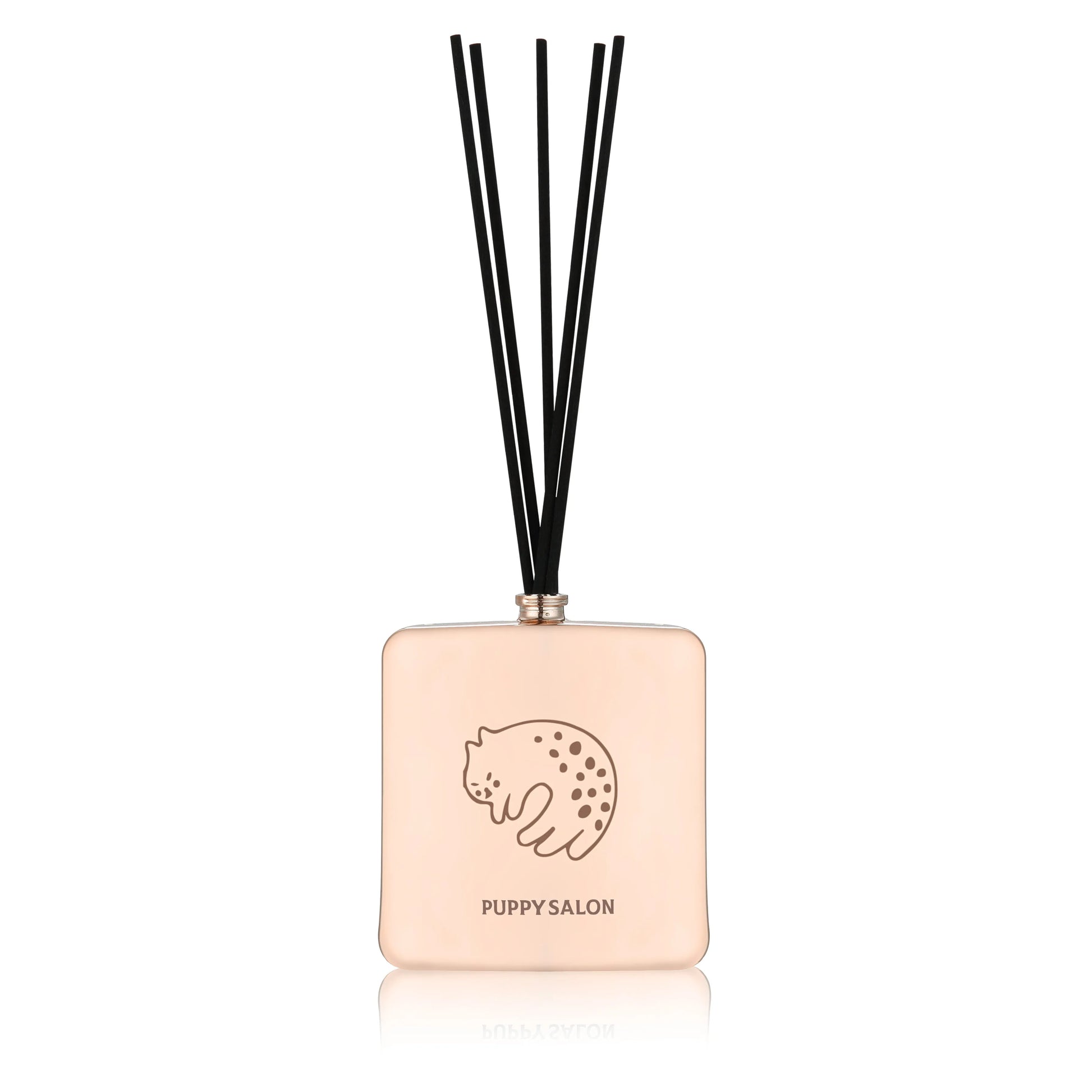 Isolated view of the Puppy Salon cat-inspired reed diffuser. The rose gold glass bottle with intricate cut-out designs adds a modern touch to any space.
