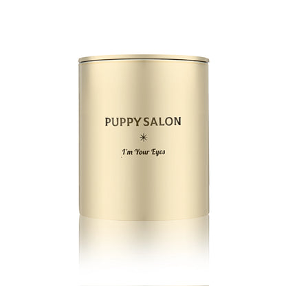 Isolated view of the Puppy Salon 'I am your eyes' candle. The gold cut-out glass jar creates a warm, glowing pattern when lit.