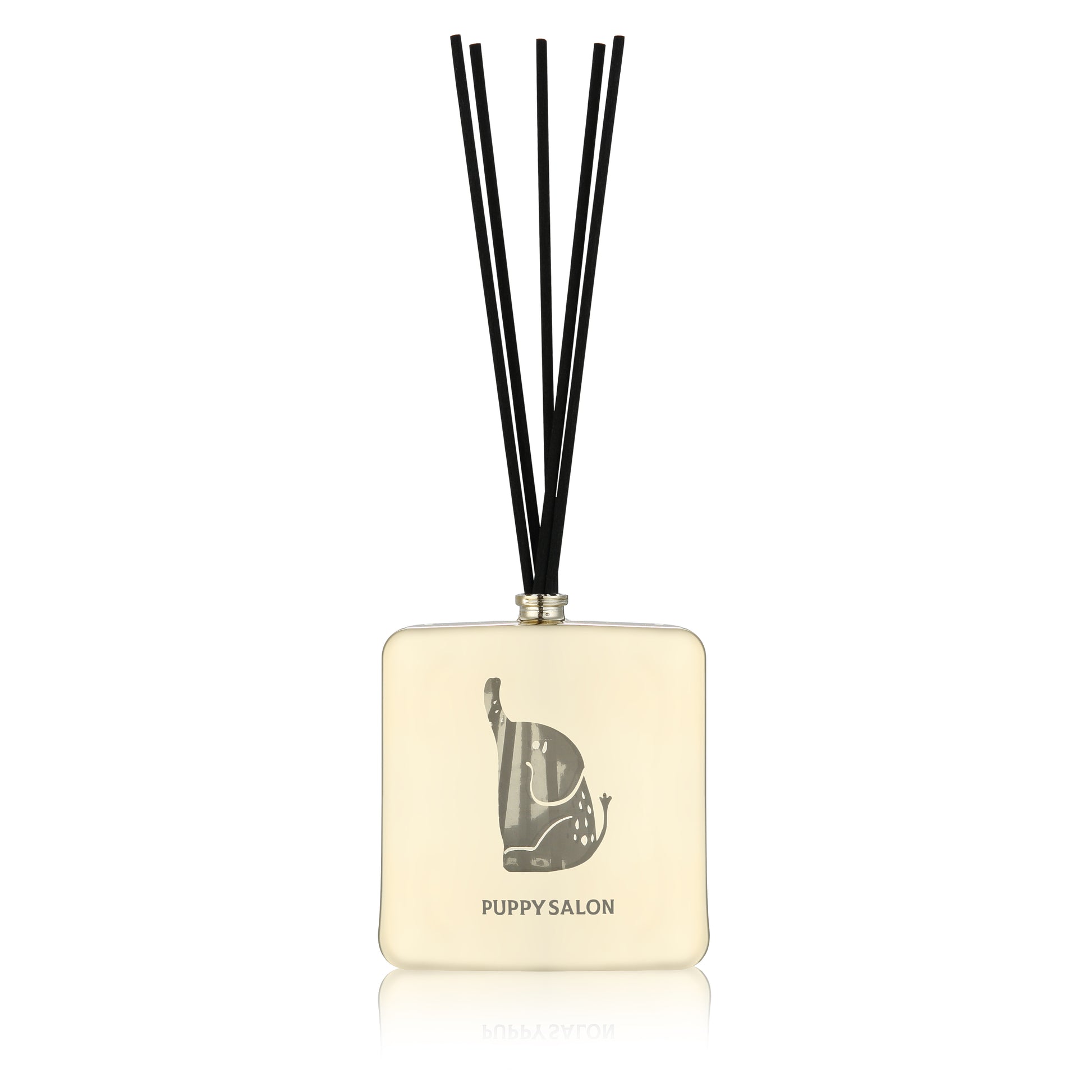 Isolated view of the Puppy Salon reed diffuser. The champagne gold glass bottle features intricate elephant cut-out designs, creating a play of light and liquid.