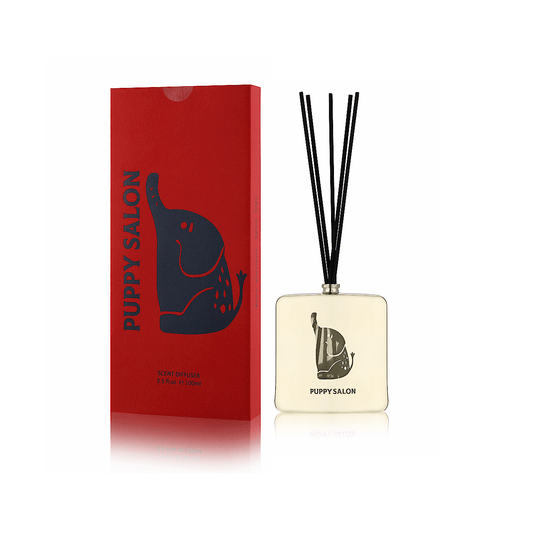 The Puppy Salon 'Journey of the Elephants' reed diffuser with its striking red gift box. Features a champagne gold cut-out glass vessel for elegant home decor.