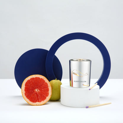 Lifestyle image of the Puppy Salon whale-inspired candle surrounded by fruits, representing its fresh, floral-citrus fragrance notes.