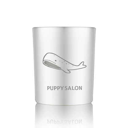 Isolated view of the Puppy Salon whale-inspired candle. The silver cut-out glass jar creates a wonderful, glowing pattern when lit.
