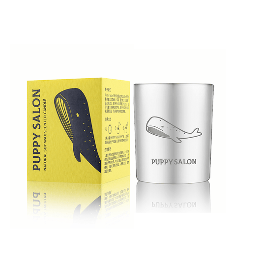 The 'Whale song of the galaxy' candle by Puppy Salon with its gift box. Features a silver cut-out glass jar with whale designs.