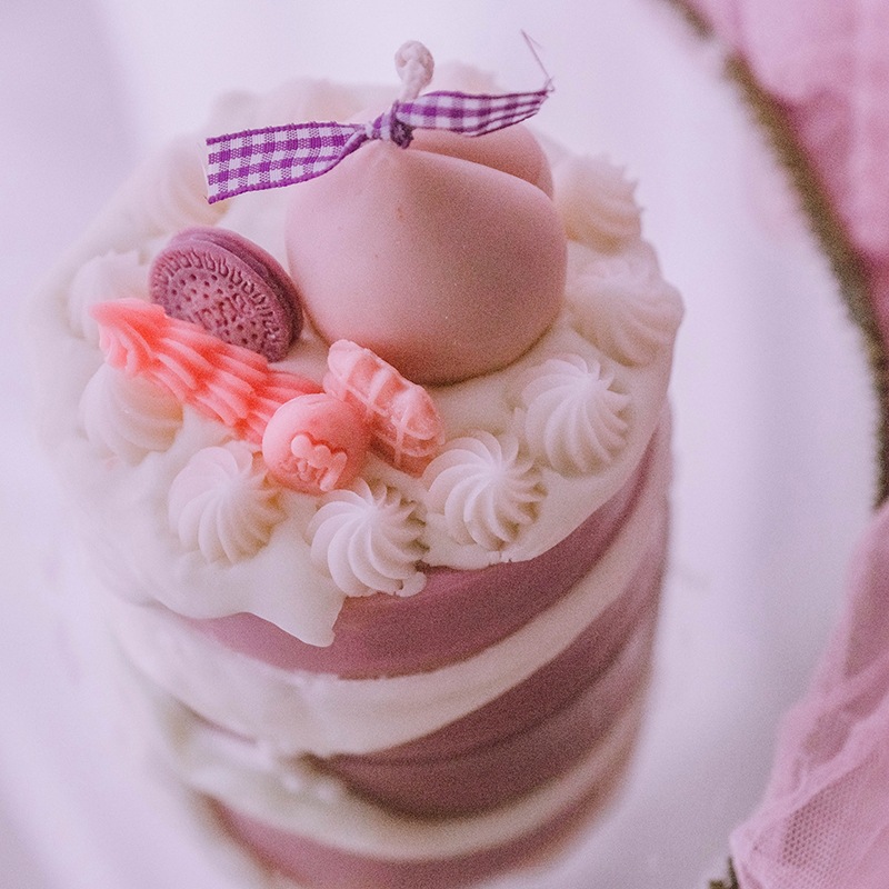 A closer look at our dessert candle design, topped with delicate frosting and a signature bow.